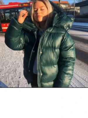 Mörkgrön pufferjacka med huva - Säljer en mörkgrön pufferjacka med stor, mysig huva och dragkedja framtill. Väldigt eftertraktad och helt slutsåld. Jackan är quiltad och har en oversized passform. Litet hål som är igensytt💗