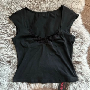 Svart topp med spetsdetalj - Snygg svart topp med spetsdetalj vid bysten