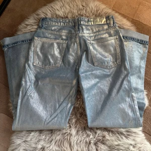 Metallic silver jeans med rak passform - Snygga metallic silverfärgade jeans med rak passform. Jeansen har en glansig yta som verkligen sticker ut och ger en cool look. 