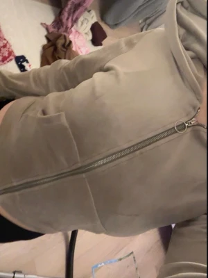 Beige mjukisbyxor med dragkedja - Säljer ett par beige mjukisbyxor med stor ficka och snygg dragkedjedetalj längs sidan. Byxorna har en relaxed passform och är perfekta för chill dagar. Materialet känns mjukt och skönt mot huden.