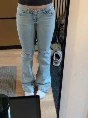 Ljusblå bootcut jeans med hål - Säljer ett par ljusblå jeans med bootcut passform för att jag har ingen användning för dem längre. Dem är använda och är lite slitna längst nere men inget som syns. 