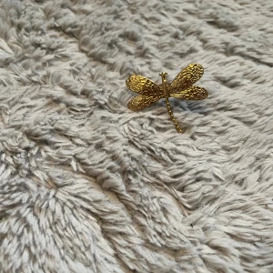 Guldfärgad trollslända ring - Unik ring i form av en trollslända i guldfärg. Vingarna har ett detaljerat, texturerat mönster som ger en cool och naturinspirerad look. Perfekt accessoar för dig som gillar smycken med djurmotiv och vill sticka ut lite extra.