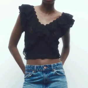 Svart blus med volanger - Säljer en svart croppad blus med v-ringad hals och volangdetaljer från Zara❣️❣️använd 1 gång