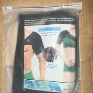 Shoulder Support Brace Axelstöd med tryckplatta - Universalstorlek - Ny axelstödsskena i förpackning, universal storlek för både män och kvinnor. Justerbar sleeve med tryckkudde, passar höger och vänster axel. Perfekt för smärtlindring, idrottsskador eller återhämtning. Produkten är oöppnad och i nyskick.