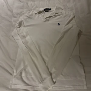 Vit pikétröja från Polo Ralph Lauren - Vit långärmad pikétröja från Polo Ralph Lauren. Som det ses på sista bilden har tröjan en liten fläck som förmodligen går bort i en tvätt. Jag säljer tröjan för den är för liten för mig nu. Om det är funderingar är det bara att skriva så svara jag så snabbt som möjligt.