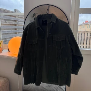 Grön manchester overshirt från Zara - Grön oversized jacka från Zara i grov manchester med snygga knappar framtill och på ärmsluten. Jackan har två bröstfickor med lock och sidofickor, samt råa kanter vid ärmslut och nederkant för en cool vibe. Perfekt att slänga över en hoodie.