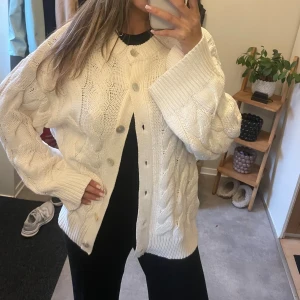 Vit kabelstickad kofta med knappar - Säljer en vit kabelstickad kofta.