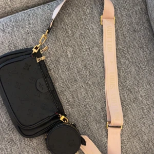 Svart väska  - Fin svart väska med rosa band, fläck i väskan och lite slitet på guldet annars fin!