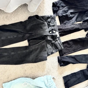 Flera jeans och shorts i olika färger - Säljer ett gäng jeans och shorts i olika färger och modeller. Här finns svarta, gråa och ljusblå jeans, samt beiga och svarta shorts. Några jeans är i klassisk denim med raka eller smalare ben, vissa shorts är i bomull och denim, ett par ljusblå shorts har slitningar framtill.