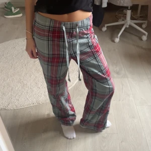 Rutig pyjamasbyxor från H&M XS - Säljer ett par rutiga byxor från H&M i storlek XS. De har en loose passform, snörning i midjan och är tillverkade i 100% bomull. Färgerna är röd och grå med ett klassiskt rutmönster. Perfekta för chill dagar hemma eller när du vill vara extra comfy.