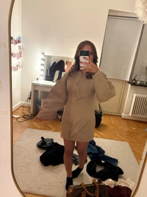 Beige kort klänning med puffärm - Snygg beige kort klänning med markerad midja och breda puffärmar.  Jag säljer den då den tyvärr inte kommer till användning för att den sitter lite för tajt!🥰🥰