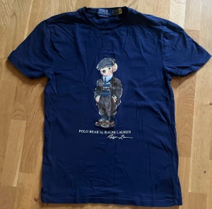 Polo Bear t-shirt Ralph Lauren - Snygg mörkblå t-shirt från Polo Ralph Lauren med ikoniskt Polo Bear-motiv på bröstet. Modellen är custom slim fit och har korta ärmar. Tillverkad i mjuk bomull och perfekt för en stilren look. Köpt i Ralph Laurens butik.