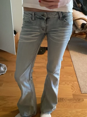 Bootcut ljusblå jeans med slitningar - Säljer ett par ljusblå bootcut jeans med snygg detalj framtill. Älskar dom, men de kommer inte till användning!🥰 Storlek 27/32, passar perfekt för mig som brukar bära S och är ca 170cm
