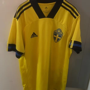 Gul Adidas tröja svenska landslaget - Bilderna visar en gul Adidas fotbollströja för svenska landslaget, inte skor. Ingen skobeskrivning kan ges.