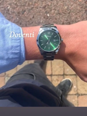 Silverfärgad grön  klocka x Doventi  - 🌟 Doventi - Helt ny och oanvänd klocka i toppskick! 🌟 🎁 Levereras komplett med originalbox. ✨ Perfekt skick, garanterat utan defekter. ⚙️ Enkel justering för optimal passform. 🚀 Snabb leverans samma dag – direkt till dig!
