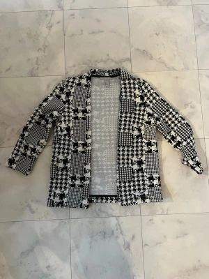 Svartvit rutig cardigan jacka H&M XS - Snygg svartvit cardigan jacka från H&M i storlek XS. Jackan har ett rutigt mönster med olika block och är stickad i mjukt material. Den är öppen framtill och har långärmade ärmar, perfekt för lager på lager och en cool look.