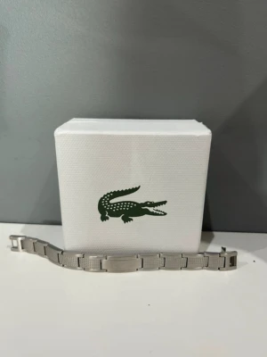Lacoste armband orginal - Bilderna visar ett silvrigt armband från Lacoste. Äkta och kommer i orginalförpackning 
