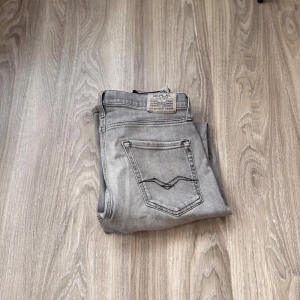 Replay grå jeans straight fit - Säljer ett par grå jeans från Replay med klassisk femficksdesign och raka ben. Storleken är svår för lappen har tvättats bort men de sitter perfa på någon som är mellan 169-175. Jeansen har en snygg tvättad look och detaljerade bakfickor med Replay-logga. Materialet är mjukt jeans och passformen är normal med midwaist. Tvättas och stryks noggrant äfter köp! Kontakta vid fler bilder eller frågor!