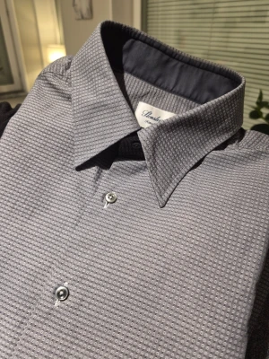 Grå mönstrad skjorta från Stenströms - Snygg grå skjorta från Stenströms med diskret prickigt mönster och klassisk krage. Skjortan har långa ärmar, knappar framtill och vid manschetten. Materialet är mjukt och känns som bomull, perfekt för dig som gillar stilrena detaljer.