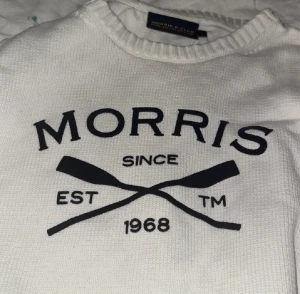 Vit stickad tröja från Morris Club - Säljer en vit stickad tröja från Morris Club med svart tryck framtill och texten 'Morris Since 1968' samt två korsade åror. Tröjan har rund hals och ribbade muddar. Perfekt för dig som gillar klassisk och sportig stil. Storlek M psssqe S