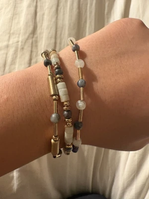 Guldigt pärlarmband med blå och vita detaljer -  DIREKT FRÅN ITALIEN!!🇮🇹 går att köpa separata!! Säljer ett snyggt armband med guldiga metallstavar och pärlor i blått, vitt och grått. Armbandet har en modern design med blandade former på pärlorna och passar perfekt för dig som gillar att sticka ut med accessoarer. Fint att bära flera tillsammans för en cool look.