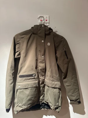 Skidjacka  8848 Altitude - Olivgrön skidjacka från 8848 Altitude med huva, flera fickor med dragkedja och knappar med logga