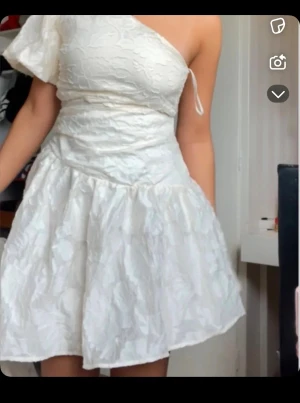Vit omlott kortklänning med blommönster - Säljer min älskade studentklänning. Använd då bara en gång inga tecken alls använd, självklart tvättat. Köptes på Plick men har ingen aning på märket eller storlek. Har gjort klänningen större så den passar mig som har storlek M hos en skräddare. Har en nyans av krämvit färg med blommigt diskret mönster. Otroligt smickrade skriv till mig privat innan du köper 🫶