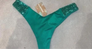 Grön bikiniunderdel med paljetter - Supersnygg grön bikiniunderdel från Calzedonia med glittriga paljettdetaljer på sidorna. Perfekt för dig som vill sticka ut på stranden! Sitter tight och har en klassisk tangaform. Materialet är mjukt och följsamt syntet.