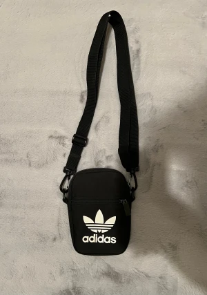 Adidas mini väska  - Säljer en mini Adidas väska som är använd, den har lite slitage vid metalldelarna. Men inga hål eller problem med dragkedjan. 