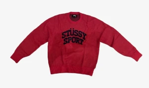 Röd stickad Stüssy Sport tröja - Säljer en röd stickad tröja från Stüssy Sport med svart logotyp framtill. Tröjan har rund hals, ribbade muddar och lång ärm. Perfekt för dig som gillar streetwear och vill ha något som sticker ut i garderoben.
