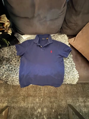 Mörkblå Polo Ralph Lauren piké - Snygg mörkblå pikétröja från Polo Ralph Lauren i slim fit. Klassisk krage, korta ärmar och två knappar framtill. Ikonisk röd logga broderad på bröstet. Tillverkad i mjuk bomull som är skön mot huden. Perfekt för dig som gillar stilren och sportig look. Är i storleken M men passar även S🙌🏼skriv vid minsta lilla fråga✌🏼Ny pris: 1500kr. Mitt pris: 699kr