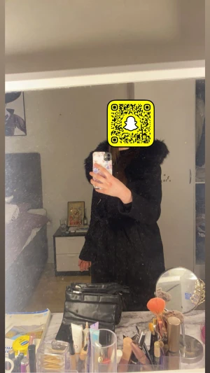 Svart kappa med fuskpäls - Säljer en svart kappa med fluffig fuskpäls runt kragen. Jackan har ett bälte i midjan för snygg passform och långa ärmar. Perfekt för dig som vill ha en stilren och varm look under höst och vinter.