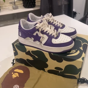 Lila och vita Bape skor - Säljer ett par Bape skor i lila och vitt i bra skick och, originalkartong och skosulor förekommer ej men  dustbag med Bape-logga förekommer.                                 Pris kan snackas om!
