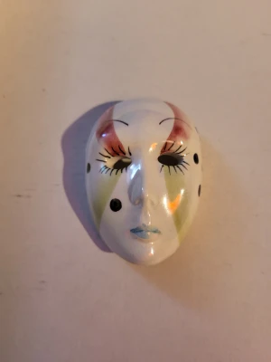 Jester mask - Delicate porcline mask with opalessant sheen. It can be hung, used as a Christmas ornament, or maybe a necklace or brooch! Some minor signs of wear on the back, but nothing at the front that I can see.  8.5cm long side, 5.5cm top of head, 4.5cm base of face, 2cm tall