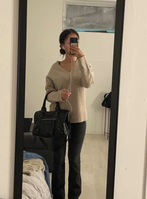 Beige stickad v-ringad tröja A VIE SU - Mysig beige stickad tröja från A VIE SU i storlek M. Tröjan har v-ringad hals, långa ärmar och breda ribbade muddar vid ärmslut och nederkant. Perfekt för lager-på-lager och chill stil. Materialet är mjukt och ger en relaxed vibe.