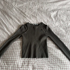 Mörkgrå ribbad långärmad topp från Zara - Säljer en trendig mörkgrå/brun tröja med cutouts vid axlarna endast använd någon gång men den har ett litet hål under armhålan men inget som syns när man använder den❤️Den är i storlek M men passar även S för jag har oftast Xs/S men den passar mig