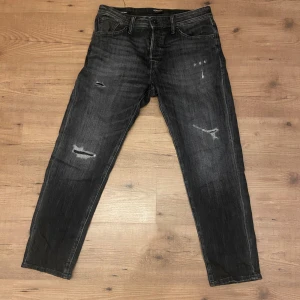 Svarta tapered jeans Jack & Jones - Säljer ett par Jack and Jones jeans i mycket bra skick då dom är använda få gånger eftersom jag köpte fel storlek och modell. Ord pris: 799. Obs märket på baksidan, vid bälteshällorna, har släppt lite i sömmen. 