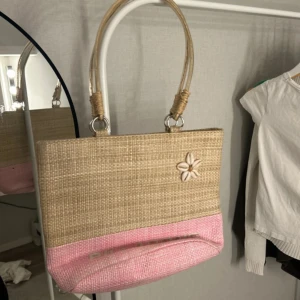 Beige och rosa strandväska Billabong - Snygg strandväska från Billabong i beige och rosa med ett coolt blommigt snäckdekor på framsidan. Väskan har två rejäla handtag och är tillverkad i ett flätat syntetmaterial. Perfekt storlek för att få med allt du behöver och har innerfack med dragkedja. Väskan har fläckar inuti sig!!! Pris kan diskuteras 🥰