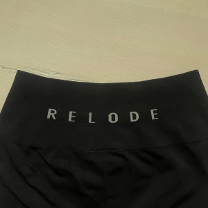 Svarta träningstights från Relode - Svarta seamless träningstights från Relode med bred ribbad linning, formar sig efter kroppen. Märket i vitt på baksidan. Stretchigt material och använda endast en gång. Ordinarie pris 699kr