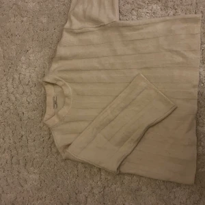 Beige ribbad stickad tröja Ginatricot - Mysig beige stickad tröja från Ginatricot i storlek XS. Tröjan har ett ribbat mönster och rund halsringning, perfekt för dig som gillar enkel och clean stil. Långärmad och i mjukt material som känns skönt mot huden.