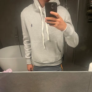 Grå ralph lauren hoodie - Grå Ralph lauren hoodie perfekt för vintern. Skick 9/10 använd endast ett fåtal gånger. Storlek S slim fit passar som storleken. Pris kan diskuteras.