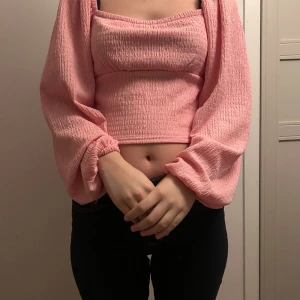 Rosa croppad blus från Bik Bok - Supersöt ljusrosa blus från Bik Bok med croppad passform och puffiga långärmar. Toppen har en smockad struktur som ger en cool textur och sitter snyggt mot kroppen.🥰🥰