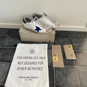 Äkta Golden Goose Superstar sneakers vit/blå - Golden Goose Superstar sneakers.        Köpte nya för 4400kr på best secret och använder ej längre. Allt og ingår.              Passar 42 och 43 skulle jag säga.               Två bokstäver har åkt av därav priset. Hör av er vid frågor ! 