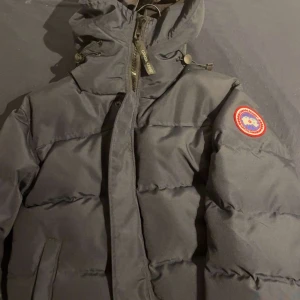 Mörkblå dunjacka Canada Goose XS - Säljer en mörkblå dunjacka från Canada Goose i storlek XS. Jackan har huva, dragkedja med logotagg, och klassisk patch på ärmen. Fylld med dun och har quiltad design för extra värme. Perfekt för kalla dagar och har en clean, urban look. Kan gå ner i pris vid snabba köp och endast seriösa köpare!