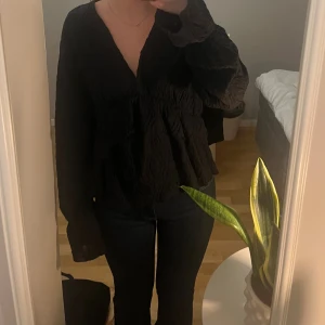 Svart volangblus - Svart blus från Gina Tricot med v-ringning och långa ärmar. Storlek xs men passar också s. Använd några gånger men i fint skick!🥰🥰