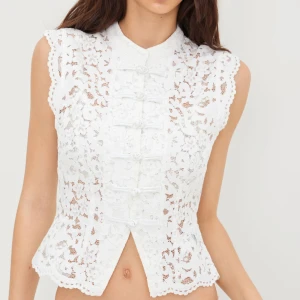 Vit spetsblus  - Supersöt vit blus i spets med blommigt mönster och dekorativa knyt framtill. Storlek 36/S