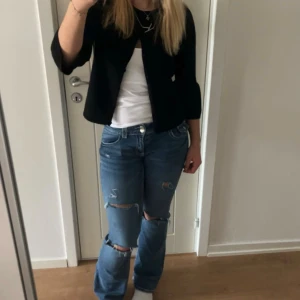 Low waist jeans med hål - Säljer ett par blå jeans med låg midja och raka ben. Jeansen har slitna detaljer och hål vid knäna för en cool, avslappnad look. Klassisk femficksmodell i denim med knapp och dragkedja framtill. Säljer pga att de ej kommer till användning men är i superfint skick, för referens så är jag 167cm lång💕hör av er vid frågor eller fler bilder. Pris kan diskuteras‼️
