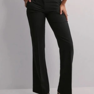 Lågmidjade kostymbyxor från Nelly, stl 32 - Super snygga svarta kostymbyxor från Nelly som är lågmidjade och bootcut. Endast använda en gång så de är som i ny skick! Köpta för 400kr. Var inte rädd för att fråga om fler bilder eller annat. Priset kan diskuteras.🥰 