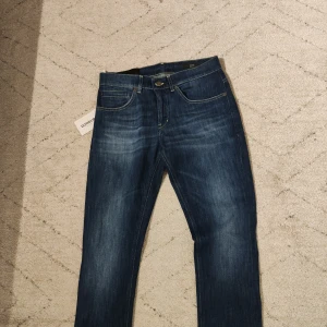 Dondup George - Helt nya jeans med tag kvar från Dondup, modell George Skinny Fit. Jeansen har klassisk femficksdesign, kontrastsömmar och en mörkblått tvätt.
