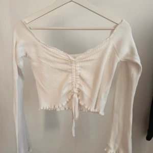 Vit stickad tröja med snörning från NAKD - Vit stickad tröja med snörning från NAKD (Linn Ahlborgs kollektion) i storlek S. Väldigt stretchig. Lite nopprig på ärmarna men annars i bra skick.